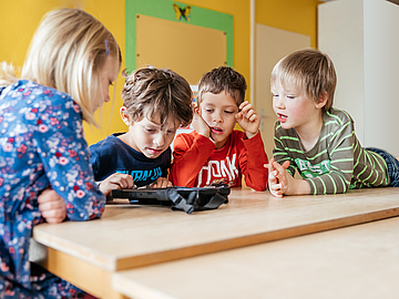 Digitaler Vorlesetag im Live-Stream: Kindergarten-Kinder schauen gemeinsam auf ein Tablet